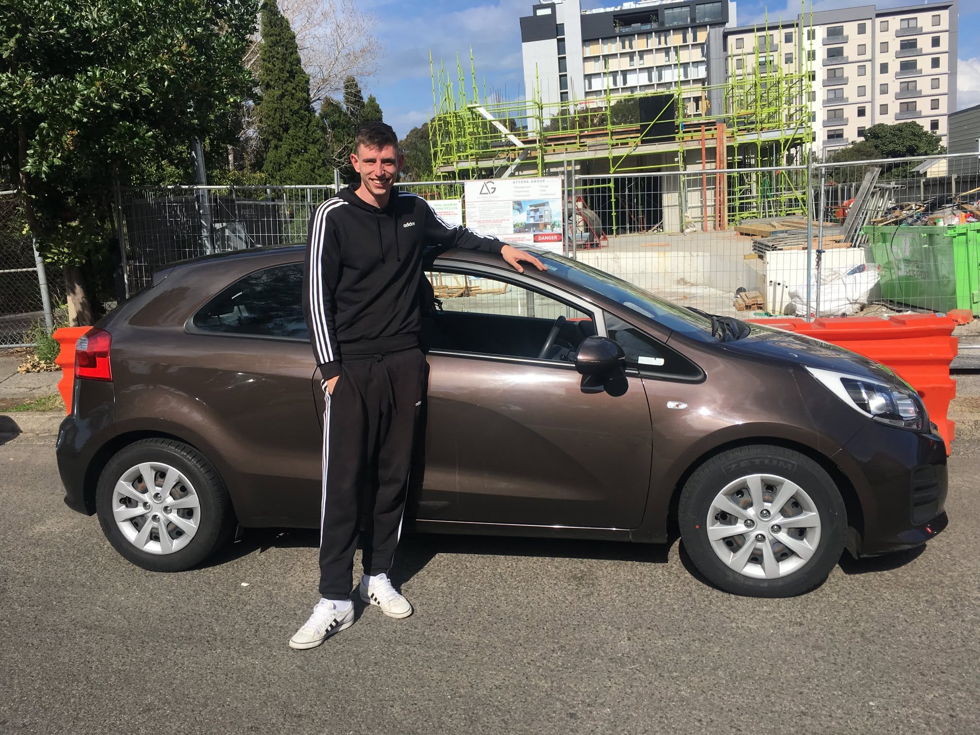 Happy CarNet renter standing beside a brown hatchback