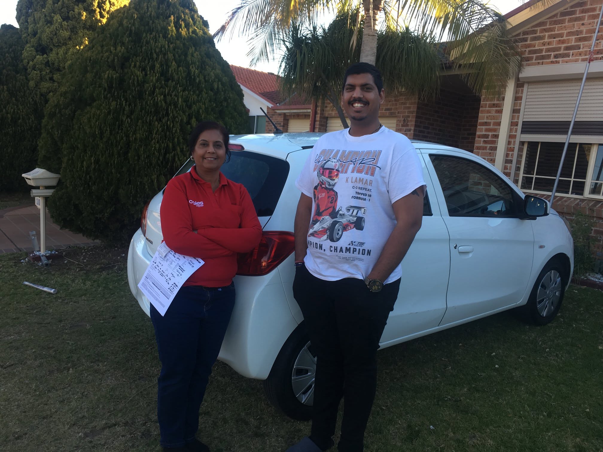 Two happy CarNet renters standing beside a white hatchback