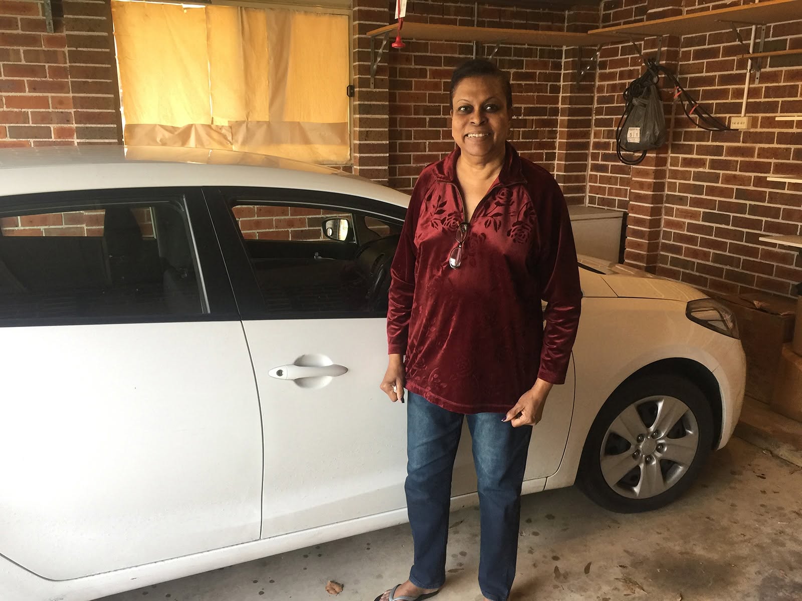 Happy CarNet renter standing beside a white sedan