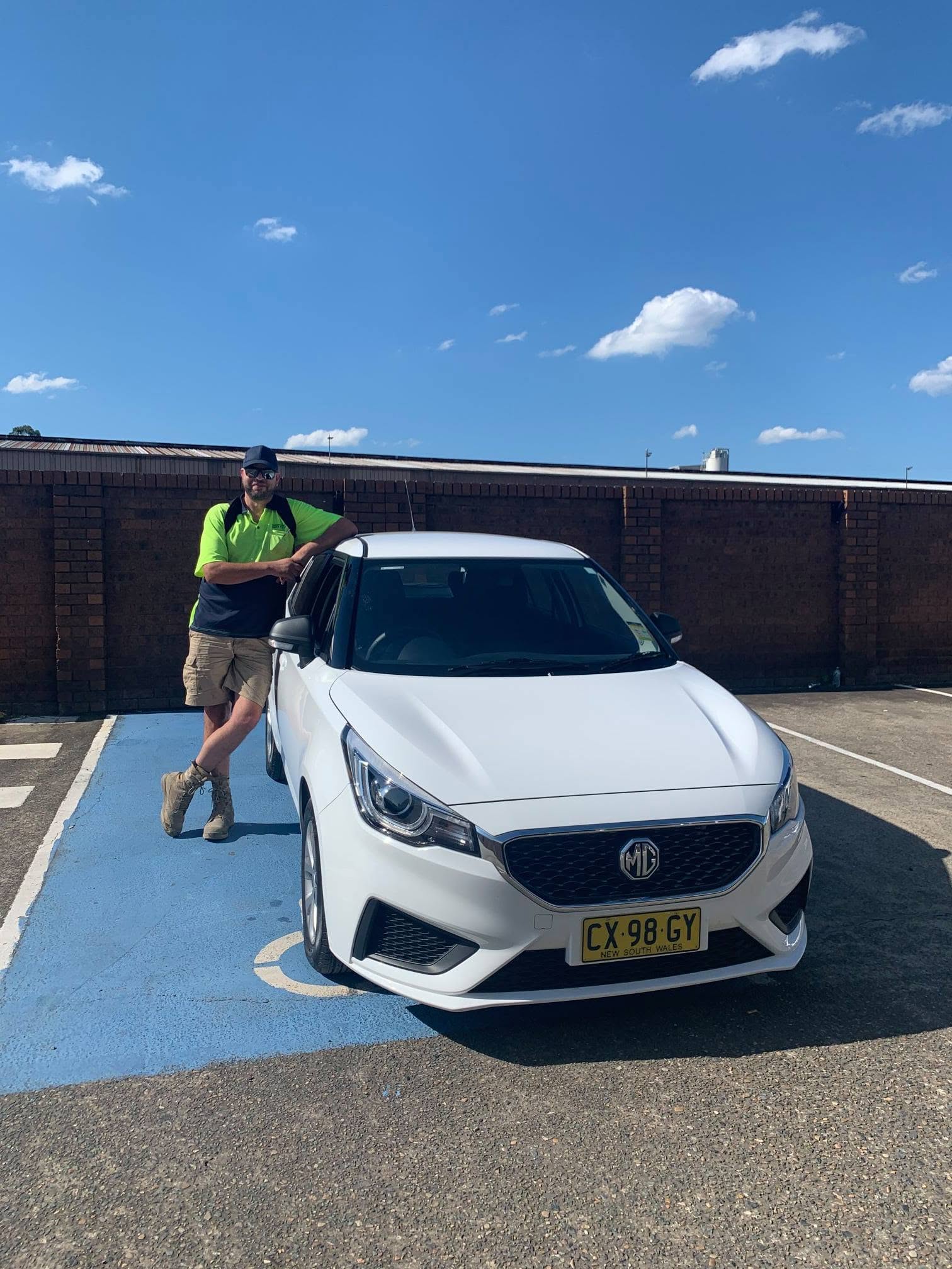 Happy CarNet renter standing beside a white MG hatchback